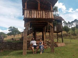 dwoje ludzi siedzących przed domkiem na drzewie w obiekcie Casa de Campo Província Minosso w mieście Farroupilha