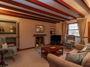 sala de estar con sofá y chimenea en Wyndhead Cottage, en Lauder