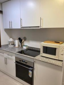 a kitchen with white cabinets and a microwave oven at Apartamento L'Estartit in L'Estartit