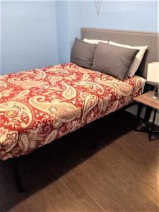 a bed with a red and gold blanket on it at Niagara Getaway in Niagara Falls