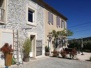 uma casa de pedra com vasos de plantas em frente em Charme au cœur des vignes em Malras