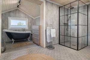 een badkamer met een bad en een glazen douche bij Koselig bolig i Lofoten / Vesterålen in Strønstad