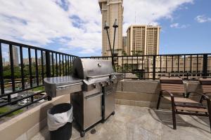 a grill on a balcony with a view of a city at Apartments at Palms Waikiki in Honolulu