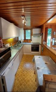 una cucina con armadi bianchi e soffitto in legno di Chalet 172 - La Boverie a Rendeux