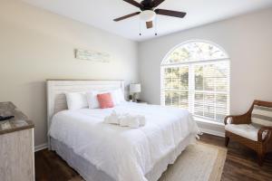 a bedroom with a white bed with a ceiling fan at Coquina Casita in Myrtle Beach