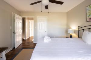 1 dormitorio con 1 cama blanca grande y ventilador de techo en Coquina Casita en Myrtle Beach