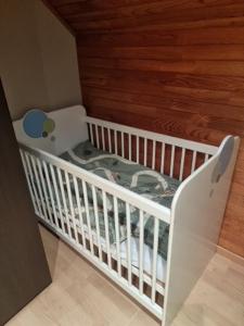 - un lit bébé blanc dans une chambre dotée d'un mur en bois dans l'établissement maison de vacances, à Halle