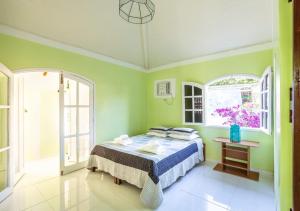 Búzios Casa Verde في بوزيوس: غرفة نوم بسرير مع جدران خضراء ونوافذ