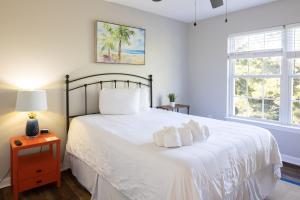 a bedroom with a bed with white sheets and a window at Coquina Casita in Myrtle Beach