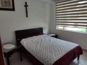 a bedroom with a bed and a cross on a window at El Oasis Fomeque in Fómeque
