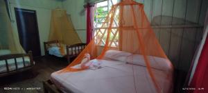 a bedroom with a bed with an orange net at Eware Refugio Amazonico in Puerto Nariño