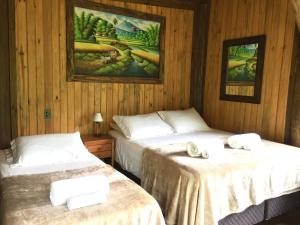 two beds in a room with wooden walls at Cabana com vista para o canyon in Praia Grande