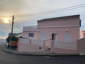 a pink house on the side of a street at Casa da Ribeira - Mosteiros in Mosteiros