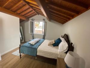a bedroom with a bed with blue sheets and a window at Casa da Ribeira - Mosteiros in Mosteiros