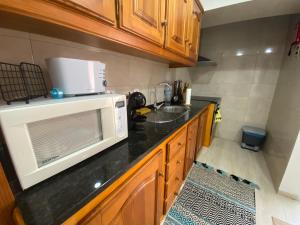a kitchen with a microwave and a sink at Casa da Ribeira - Mosteiros in Mosteiros