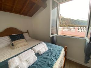 a bedroom with a bed with towels and a window at Casa da Ribeira - Mosteiros in Mosteiros