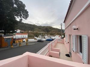 a balcony of a pink building with a street at Casa da Ribeira - Mosteiros in Mosteiros