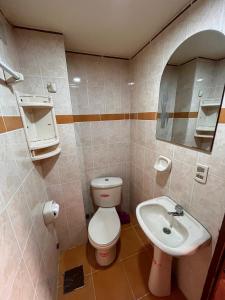 y baño con aseo y lavamanos. en Hostal Iskanwaya, en La Paz