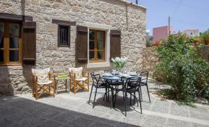 a table and chairs in front of a stone house at Mesogi Cottage in Mesoyi