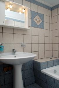 ein Badezimmer mit einem weißen Waschbecken und einer Badewanne in der Unterkunft Zouzoula House in Milína