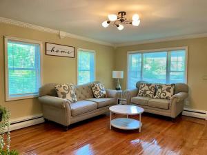 a living room with two couches and a table at Forest and River Side Tranquil House in Montague