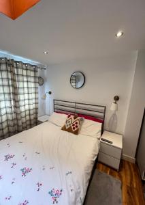 a bedroom with a bed with white sheets and a mirror at South London Private Guest Studio in Sydenham