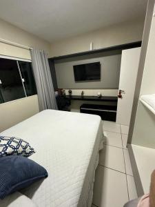 1 dormitorio con 1 cama blanca y TV en Casa aconchegante, en Florianópolis