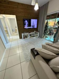 sala de estar con sofá y TV de pantalla plana en Casa aconchegante, en Florianópolis