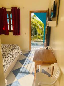 Zimmer mit einem Bett, einem Tisch und einer Tür in der Unterkunft Pousada 277 in Foz do Iguaçu