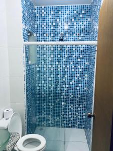 uma casa de banho com um chuveiro de azulejos azuis e um WC. em Pousada 277 em Foz do Iguaçu