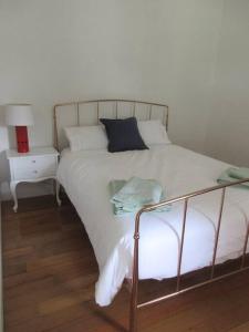 a white bed with a metal frame and a side table at The Artist's Cottage in Bendigo
