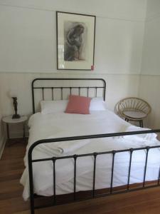 een slaapkamer met een bed met een rood kussen bij The Artist's Cottage in Bendigo