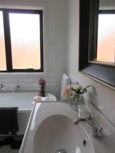 a bathroom with a sink and a tub with two windows at The Artist's Cottage in Bendigo