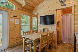 a dining room with a wooden table and chairs and a flat screen tv at Adorable little cabin #26 in Kernville