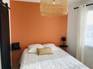 ein Schlafzimmer mit einem Bett mit einer orangefarbenen Wand in der Unterkunft Liv'In St Seb in Saint-Sébastien-sur-Loire