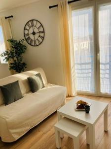 ein Wohnzimmer mit einem Sofa, einem Tisch und einer Uhr in der Unterkunft Liv'In St Seb in Saint-Sébastien-sur-Loire