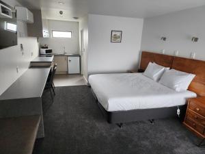 a small bedroom with a bed and a kitchen at Auto Lodge Motel in Hamilton