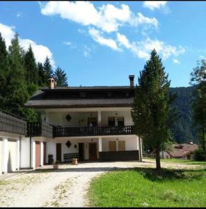 Falcade Dolomiti La Quiete Mansarda panoramica في Fregona: بيت ابيض كبير وامامه شجرة