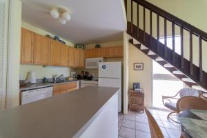 a kitchen with a white refrigerator and a staircase at Takanoha Condo in Kahuku