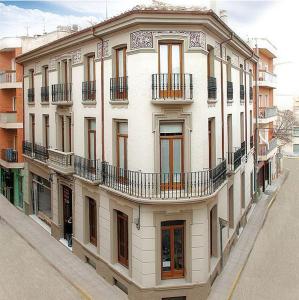 a large white building with balconies on a street at Hospedium Hotel Cañitas Maite Boutique in Casas Ibáñez