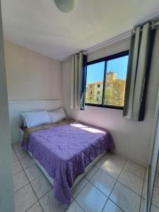 Dormitorio pequeño con cama morada frente a una ventana en Apartamento em Curitiba completo e perto de tudo, en Curitiba