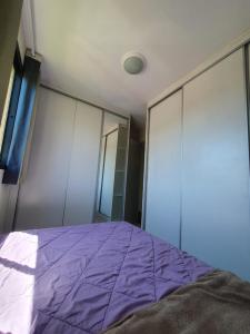 1 dormitorio con cama morada y espejo en Apartamento em Curitiba completo e perto de tudo, en Curitiba