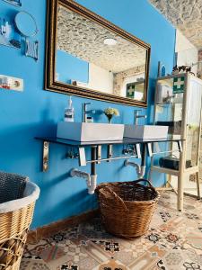 La salle de bains est pourvue d'un lavabo et d'un miroir sur un mur bleu. dans l'établissement Cortijo el Alcornocal, à Malaga