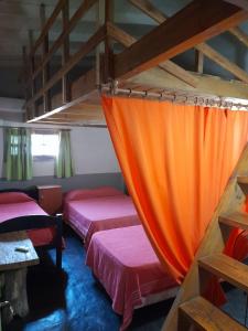 2 camas en una habitación con cortina naranja en LA CRIOLLA en Puerto Iguazú