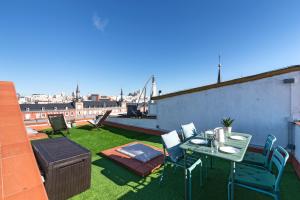 eine Terrasse mit einem Tisch und Stühlen auf dem Dach in der Unterkunft Historic penthouse Plaza Mayor in Madrid in Madrid