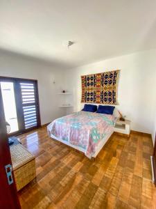 a bedroom with a bed and a wooden floor at Casa Egípcia em Morro branco - na quadra da praia in Morro Branco