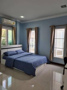 een slaapkamer met een bed met blauwe muren en ramen bij การ์เด้นโฮม By คุณโทนี่ 