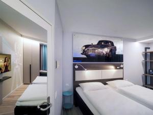 a room with two beds and a picture of a car at ibis Locarno in Locarno