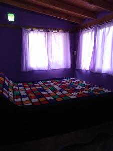 Habitación oscura con 1 cama y 2 ventanas en Aldea Hippie en Los Reartes