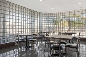 a restaurant with tables and chairs and a wall of windows at SureStay Hotel by Best Western Spring North Houston in Spring